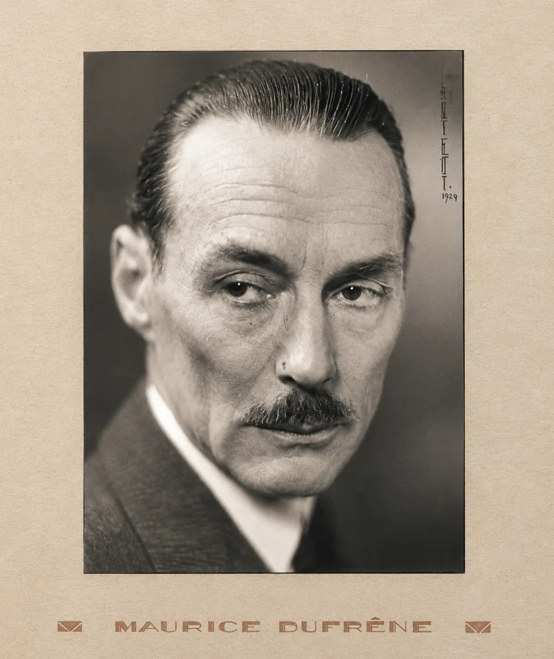 Black and white portrait of a man with slicked-back hair and a mustache, looking to the side.