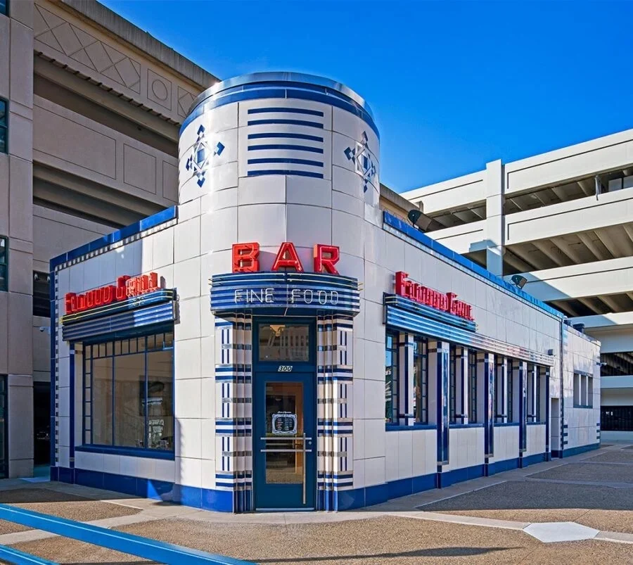Art deco style bar building with cream and blue tiled exterior and red neon sign reading 'BAR FINE FOOD'