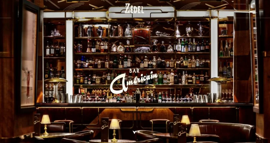 Elegant bar interior with shelves filled with various bottles of liquor, warm lighting, and leather seating.