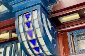 Close-up of an architectural detail featuring a curved structure with blue triangular glass inserts and metal framework.