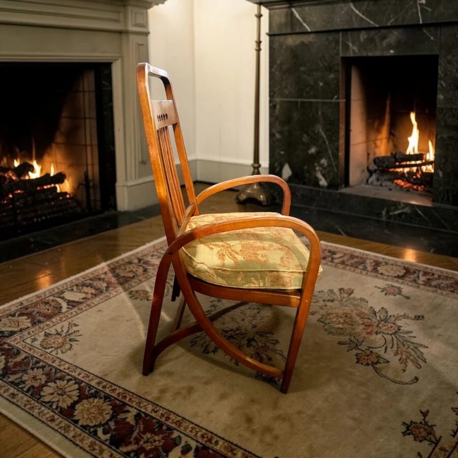 Wooden chair with cushioned seat on patterned rug in front of two lit fireplaces.