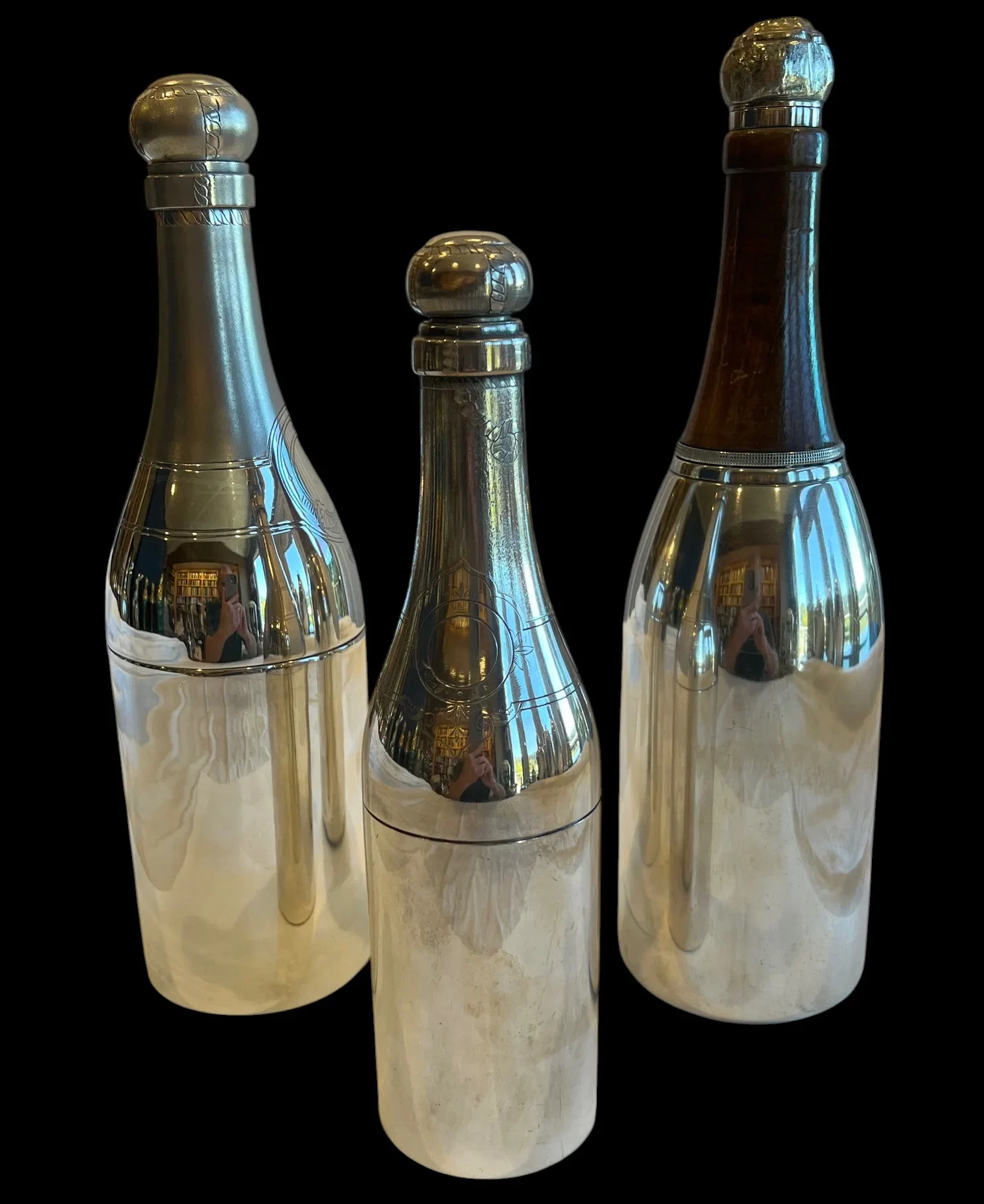 three reflective metal bottle-shaped containers against a black background