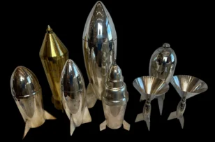 Collection of metallic rocket-shaped cocktail shakers and martini glasses on a black background