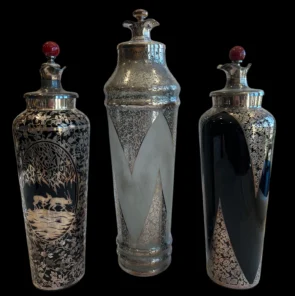 Three ornate silver decorative vases with red-topped lids on a black background