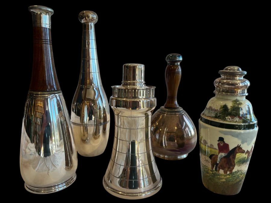 collection of vintage cocktail shakers in metal and ceramic against a black background