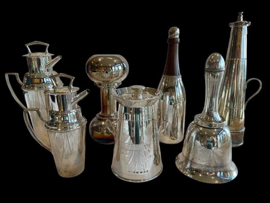 Collection of polished silver pitchers and decanters on a black background
