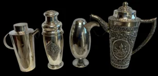 set of four ornate silver drinkware pieces against a black background