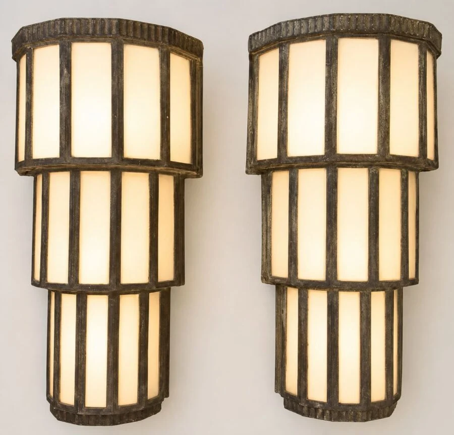 Pair of tall cylindrical wall sconces with frosted panels and dark metal frames