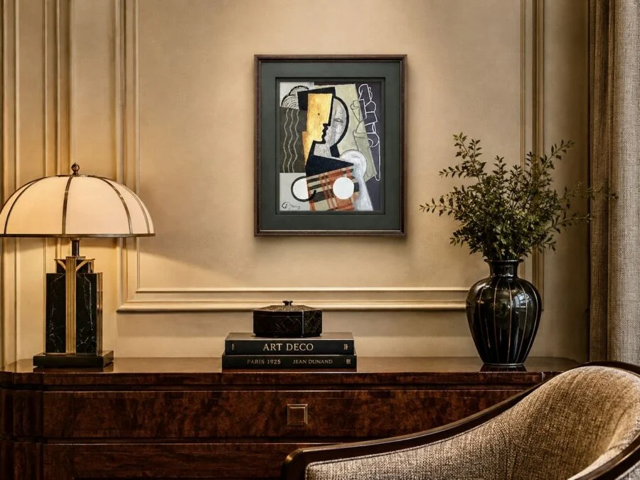 Elegant console table with lamp, abstract framed artwork, and vase with greenery in a sophisticated living room