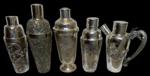 Row of ornate silver cocktail shakers with dragon and floral engravings on a black background