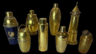 Collection of vintage brass cocktail shakers on a black background