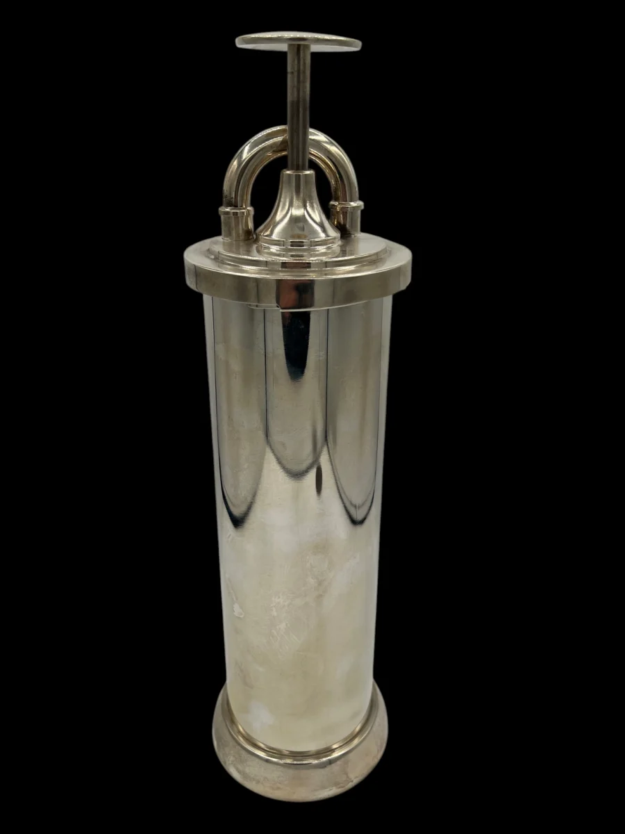 Vintage silver metal cylindrical container with plunger handle on black background