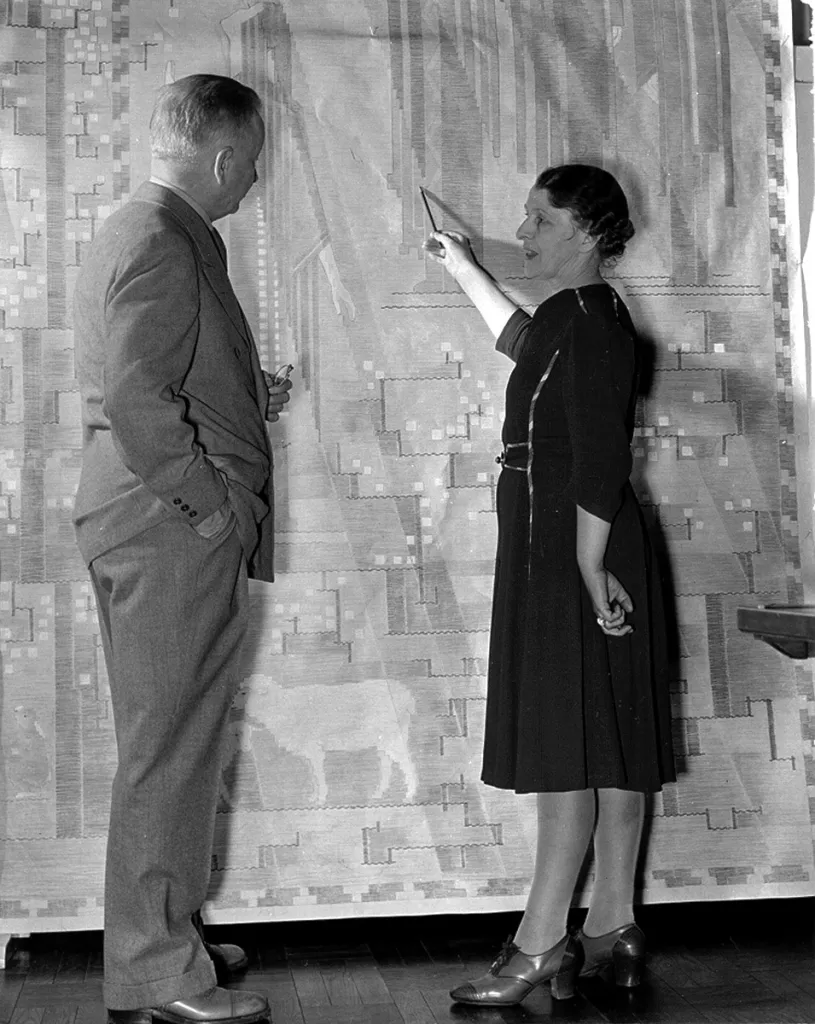 Woman pointing at large patterned wall hanging while talking with a man