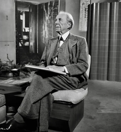 Elderly man in a suit sitting on a cushioned chair holding a large sketchbook