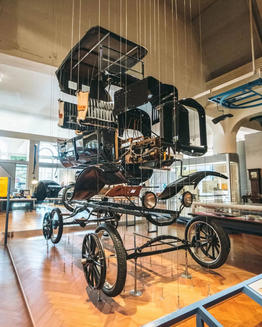 Suspended exploded-view display of an antique car in a museum gallery